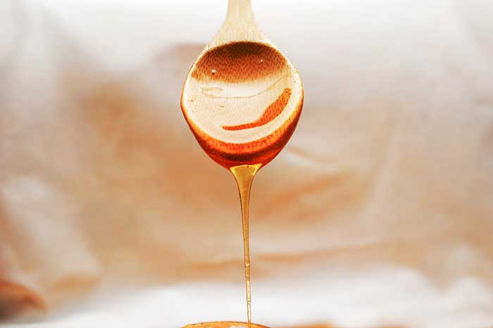Honey dripping from a wooden spoon