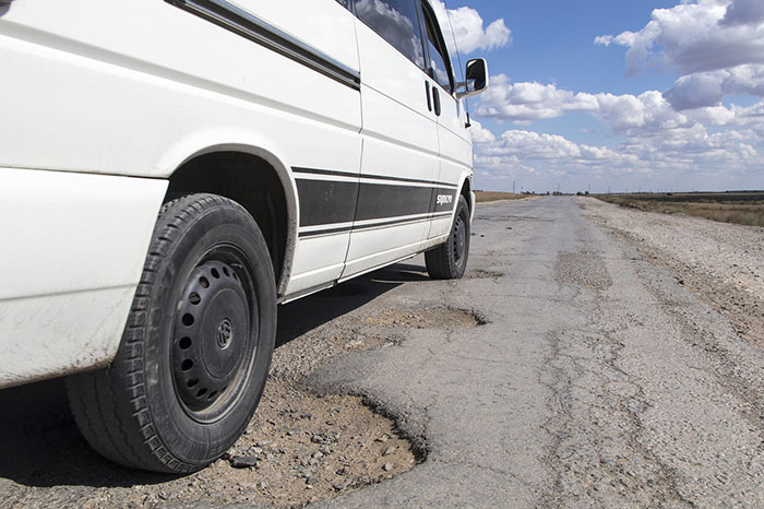 potholes on the road with car