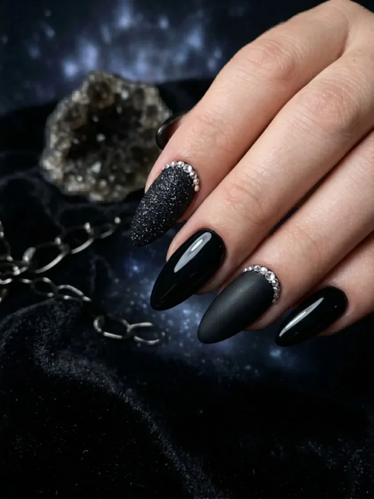 Monochromatic black almond nails combining velvet matte finish, high-gloss shimmer, and 3D stone accents for a dramatic birthday look
